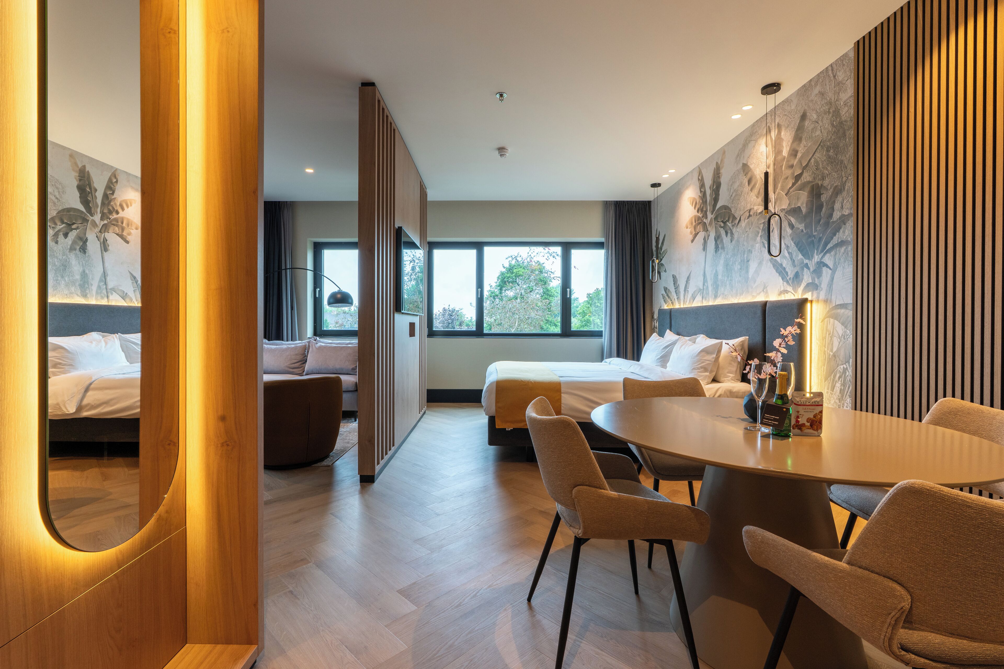 Quarto de hotel moderno com uma cama grande, uma mesa de jantar e um sofá.