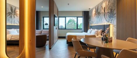 A modern hotel room with a large bed, a dining table, and a sofa.