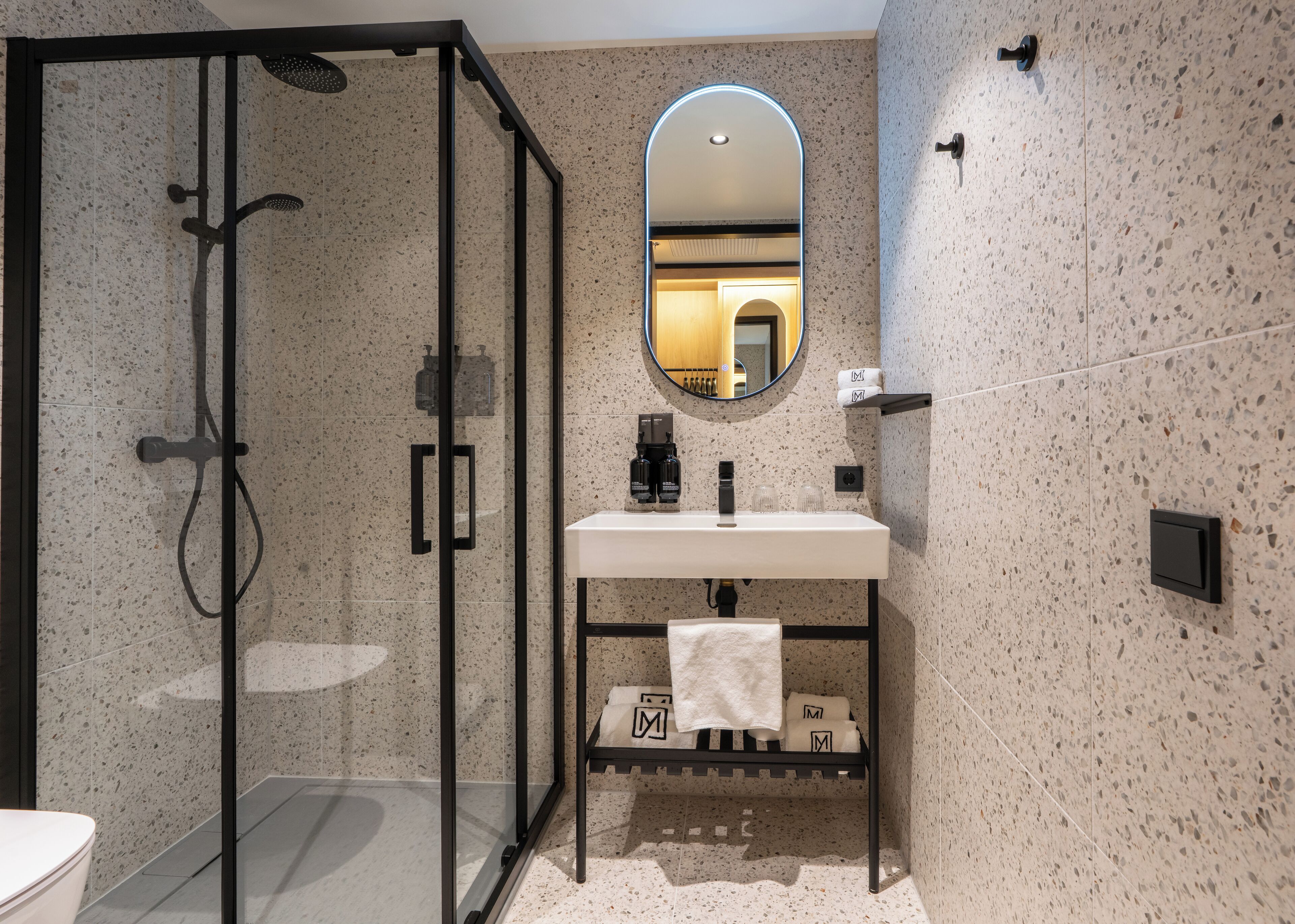 A modern bathroom with a glass-enclosed shower, a white sink with a black faucet, and a mirror above the sink.