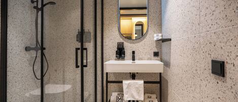 A modern bathroom with a glass-enclosed shower, a white sink with a black faucet, and a mirror above the sink.