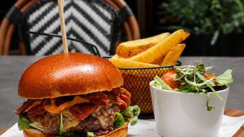 Ein Burger, Pommes und ein Salat auf einem Tisch.