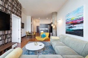 A modern living room with a sofa, a coffee table, and a dining area with chairs.