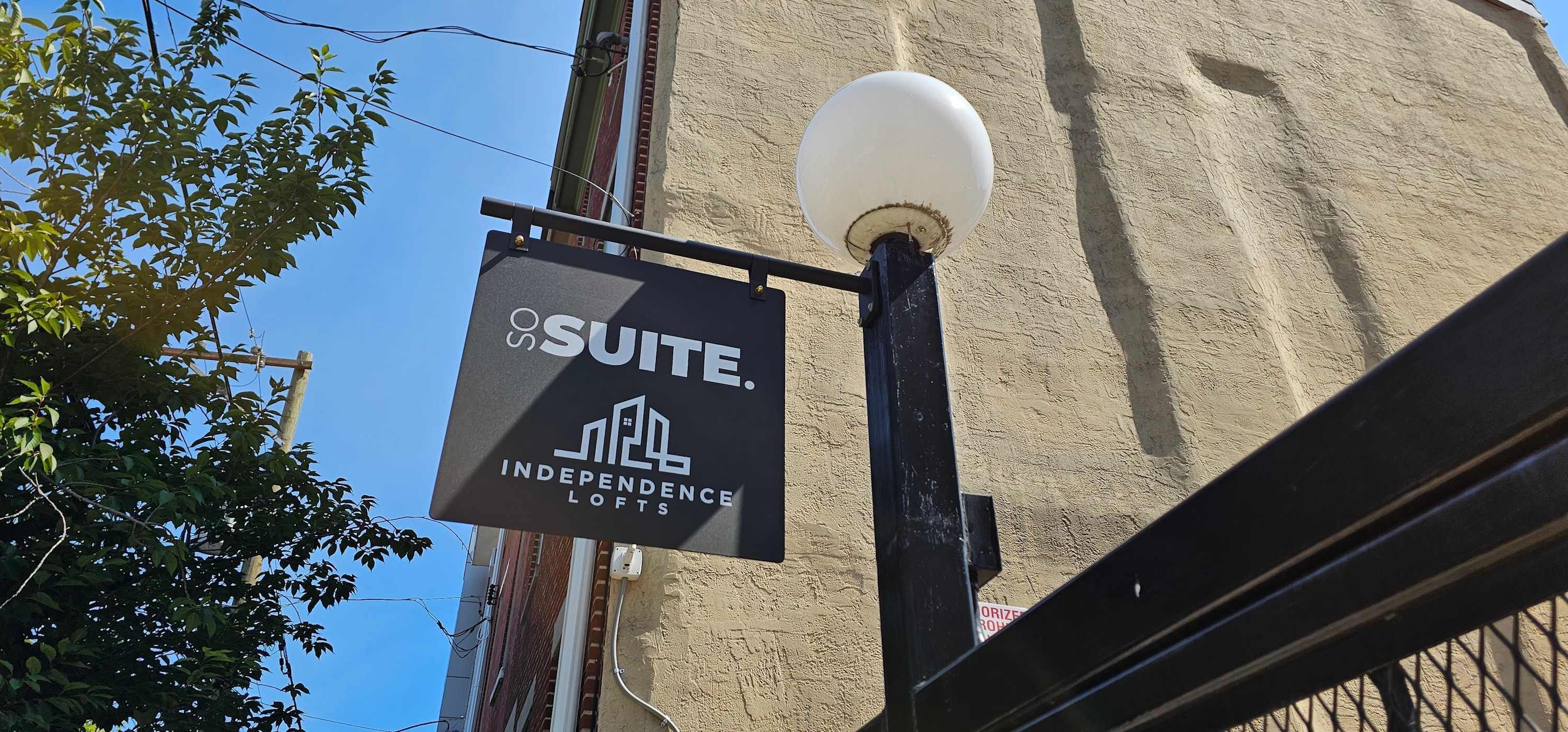 A sign for 'Suite Independence Lofts' with a clear view of the building's facade and a street lamp.