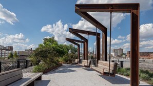 An outdoor seating area with benches and a metal structure, overlooking a cityscape. - Sosuite 2BR Penthouse w W D Gym On-site Bar (Philadelphia)