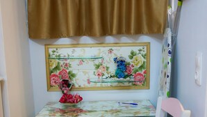 A corner desk with a floral mirror, a pink chair, and a brown curtain. - Conte Studio (Corfu)