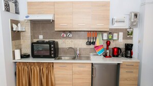A modern kitchen with a microwave, toaster, sink, and a small refrigerator. - Conte Studio (Corfu)
