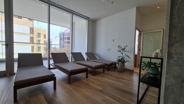 Una habitación moderna con ventanas amplias, suelo de madera y dos sillones.