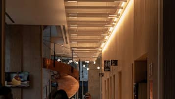 A modern restaurant interior with a long counter, hanging lights, and a large spiral sculpture.