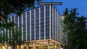 A modern building with a glass facade, a covered entrance, and a bar area visible through the windows. - Hotel Del Bono Central (San Juan)