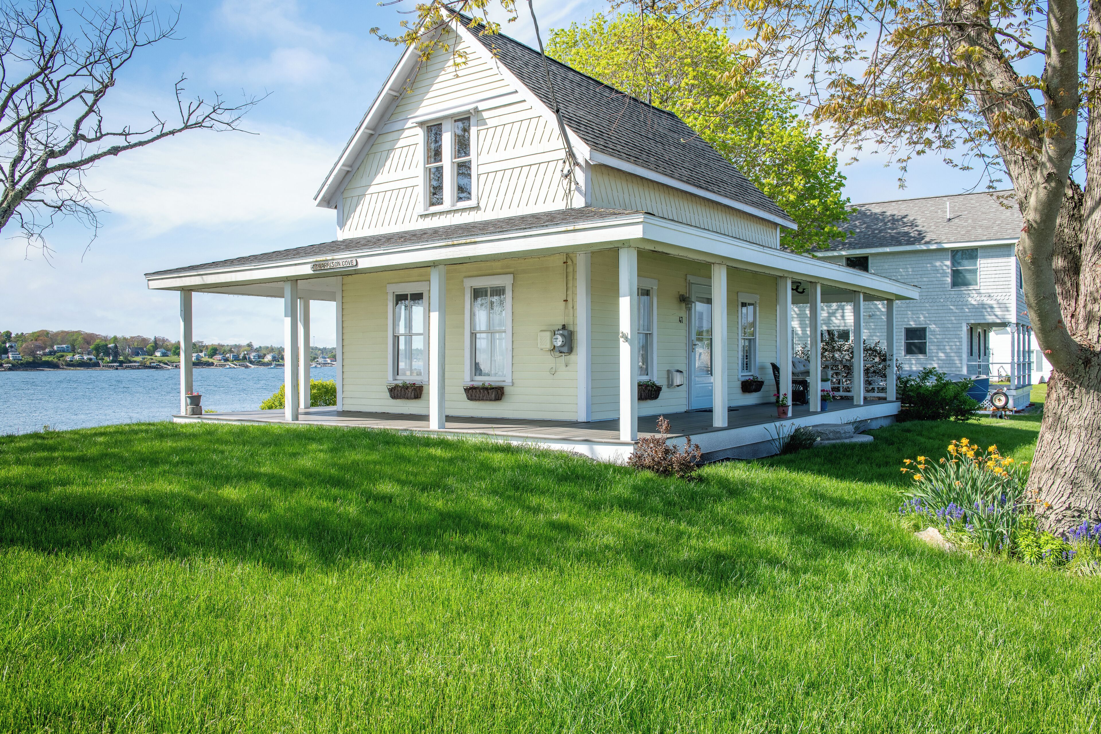 A two-story house with a covered porch and a view of the water.