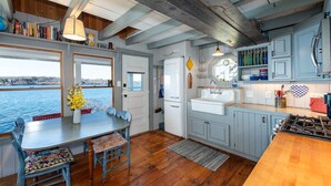 Een keuken met houten vloeren, een eethoek met tafel en stoelen, en uitzicht op het water.