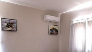 Un dormitorio con cama de madera, ropa de cama blanca, una mesita de noche negra y dos cuadros enmarcados en la pared.