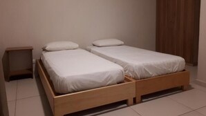 Una habitación con dos camas individuales, un armario de madera y una mesita de noche.
