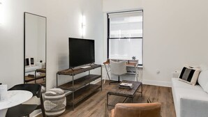 En moderne stue med et fladskærms-tv, et spisebord og en sofa.