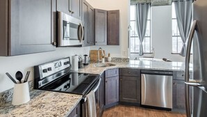 A modern kitchen with granite countertops, stainless steel appliances, and dark wood cabinets. - Sosuite 2BR Penthouse w W D Gym On-site Bar (Philadelphia)