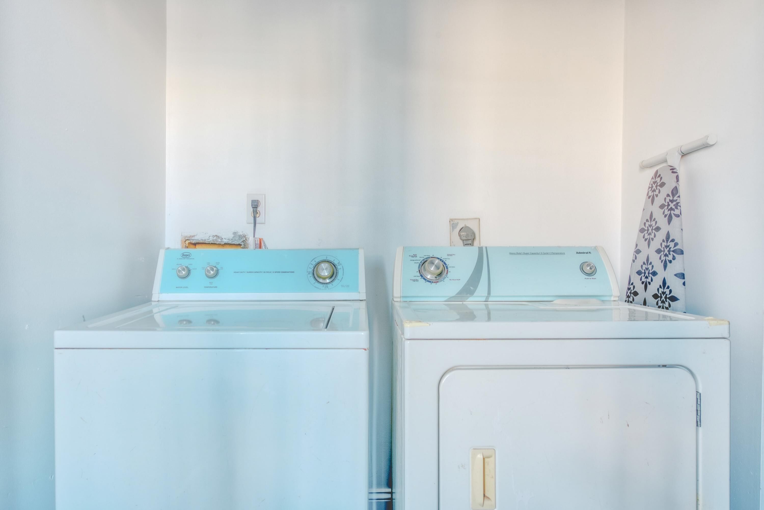 Une buanderie avec deux machines à laver blanches et un porte-serviettes orné d’une serviette à motifs floraux.