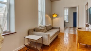 En moderne stue med en sofa, et lille bord, en gulvlampe og et TV-møbel.