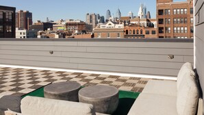 A rooftop terrace with a checkered floor, a sofa, and two round tables. - Sosuite 2BR Loft w W/d, Shared Roofdeck (Philadelphia)