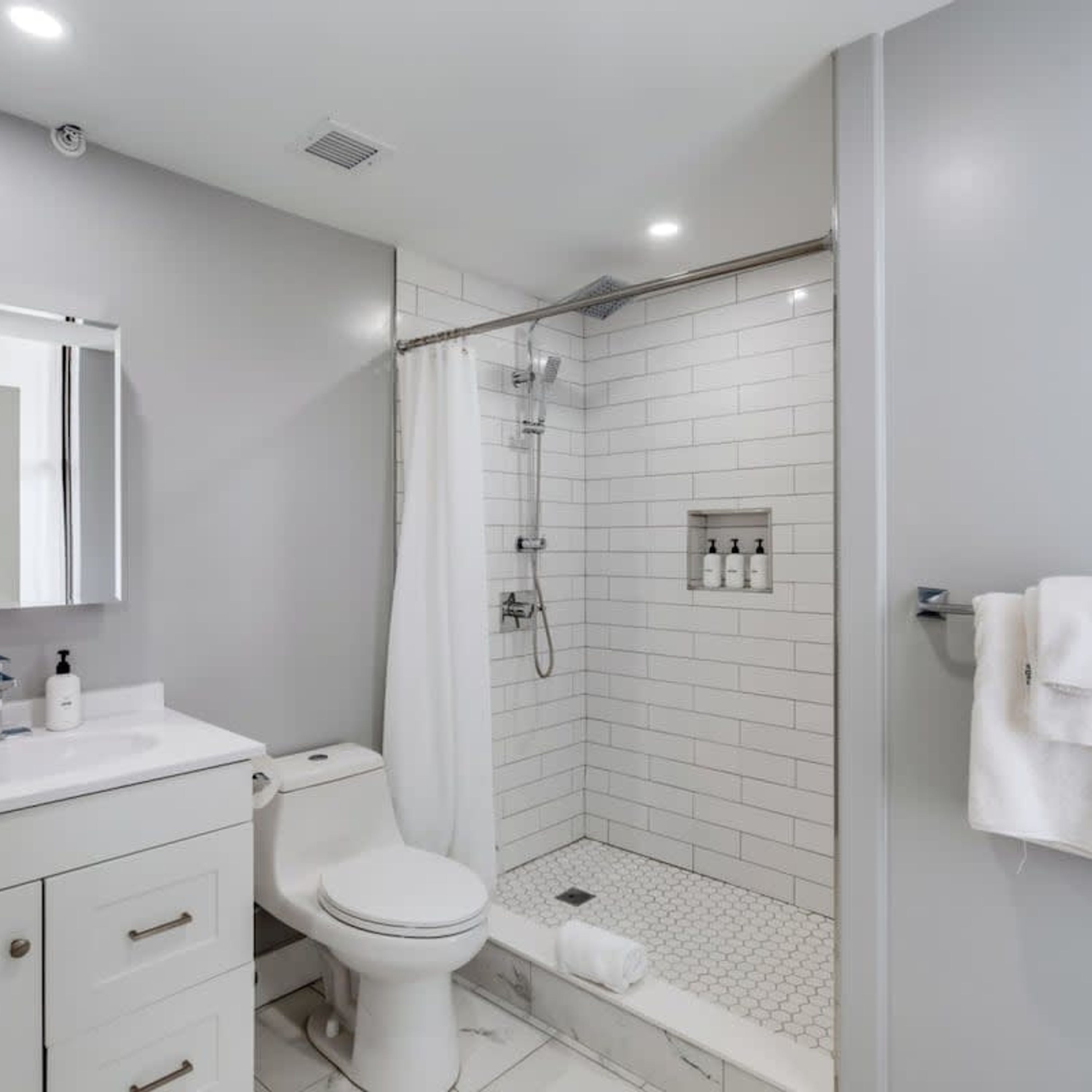 A modern bathroom with a shower, toilet, and sink.
