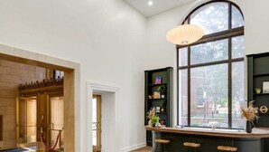 A modern interior with a wooden floor, a curved bar area with stools, a large window with a view, and a brick wall. - Sosuite 1BR Apt w W D Gym Lounge Park View (Philadelphia)