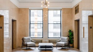A spacious lobby with two seating areas, a central coffee table, and a large window providing a view of the city. - Sosuite 1BR Apt w W D Gym Lounge Park View (Philadelphia)