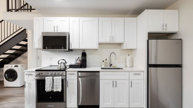 A modern kitchen with white cabinets, stainless steel appliances, and a built-in washer and dryer. - Sosuite 2BR Loft w Shared W/d, Gym, Lounge (Philadelphia)