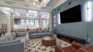A modern living room with a large TV, grey sofas, a round coffee table, and a patterned rug. - Sosuite 2BR Loft w Shared W/d, Gym, Lounge (Philadelphia)