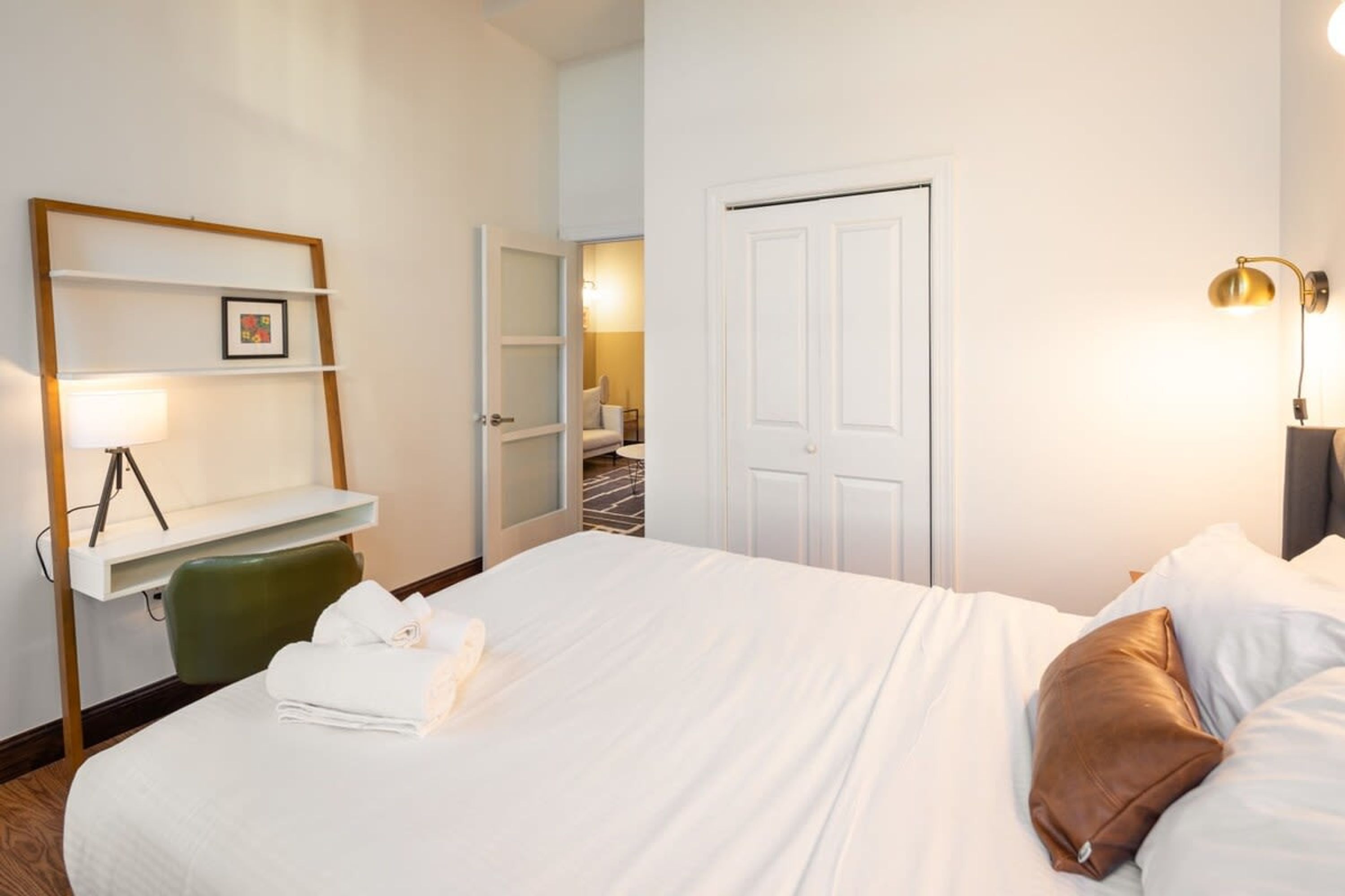 Ein Hotelzimmer mit einem großen Bett, einem Schreibtisch mit Stuhl, einem Kleiderschrank und einer Tür.