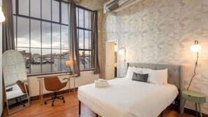 A hotel room with a large window, a bed, a desk, and a chair. - Sosuite 2BR Apt w W/d, Gym, On-site Restaurant (Philadelphia)
