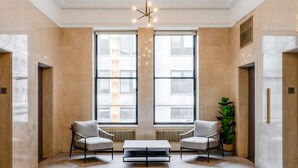 A spacious lobby with two armchairs, a coffee table, and a large window. - Sosuite Micro Studio w Shared W D Gym Lounge (Philadelphia)