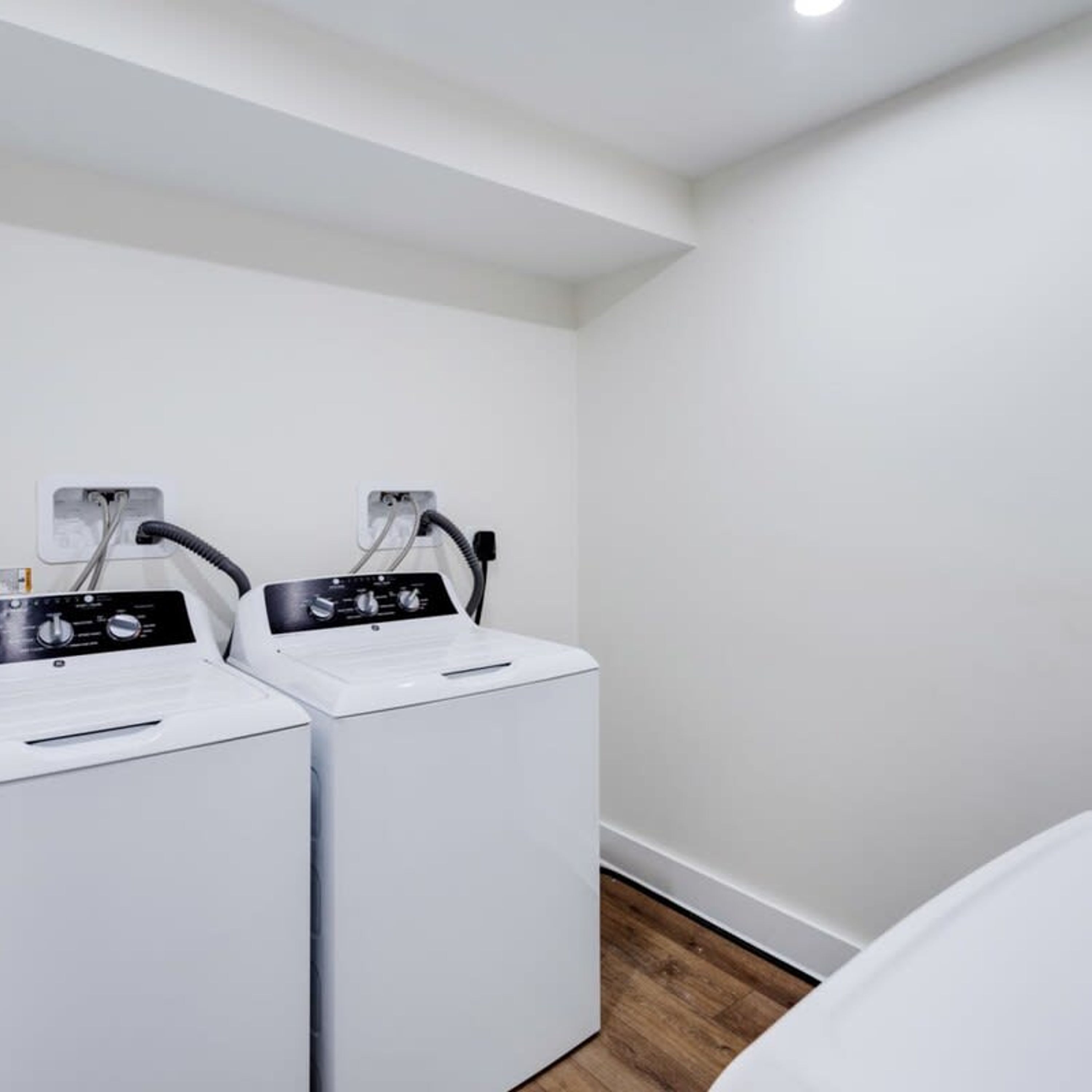 A laundry room with two white washing machines and a control panel.