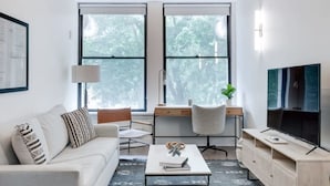 A modern living room with a sofa, coffee table, desk, and TV.