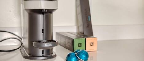 A coffee maker with a Breville brand filter basket, two blue coffee capsules, and a box with a logo.