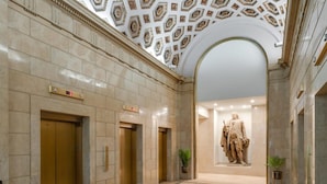 A lobby with marble floors, gold elevators, and a statue.