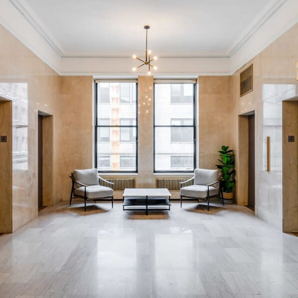 A spacious lobby with two armchairs, a coffee table, and a large window. - Sosuite 1BR Apt Acc w W D Gym Lounge (Philadelphia)