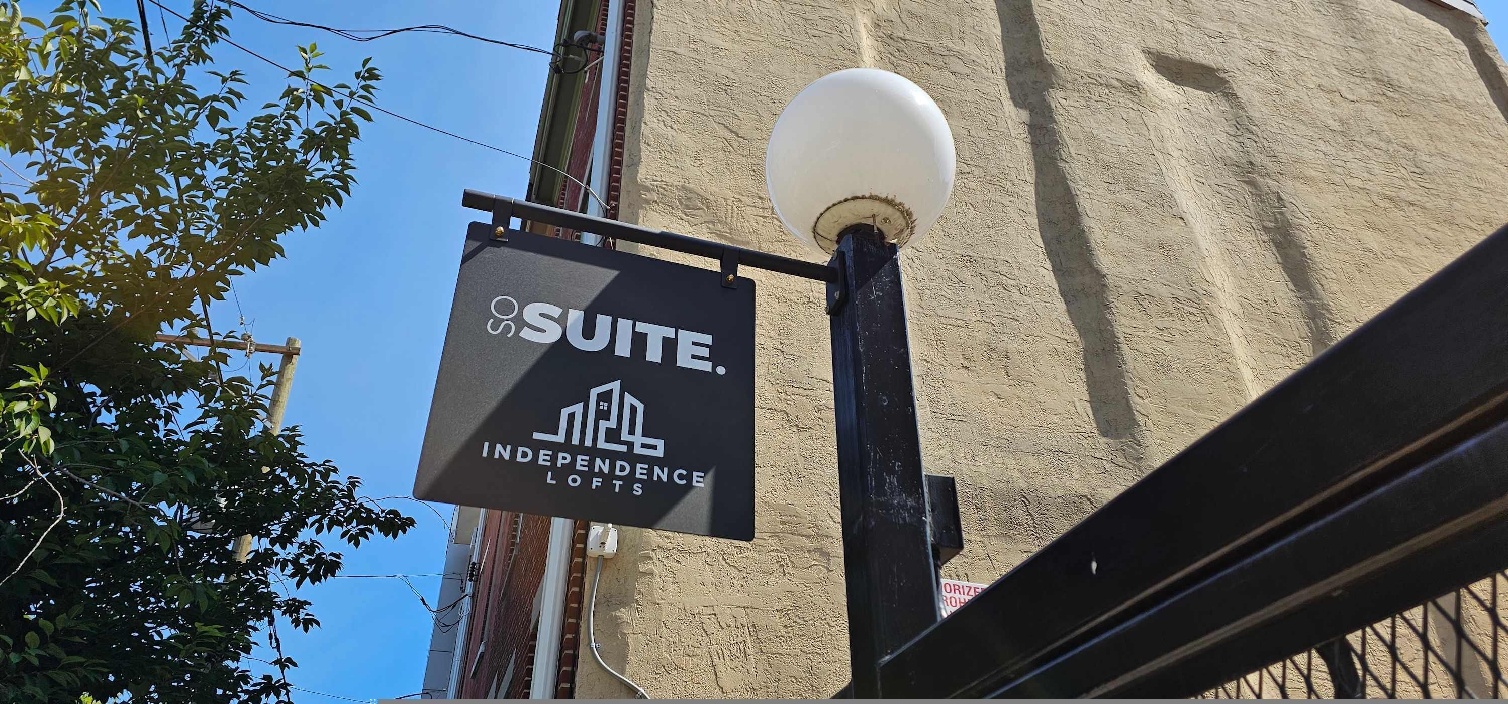 Une enseigne indiquant « Suite Independence Lofts », avec une vue dégagée sur la façade de l’immeuble et un lampadaire.