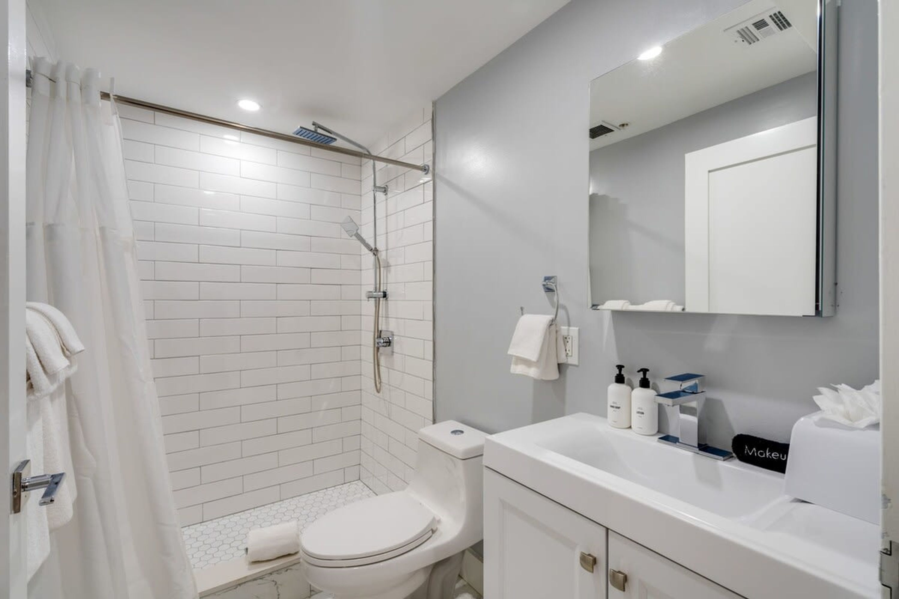 A modern bathroom with a shower, toilet, and sink.