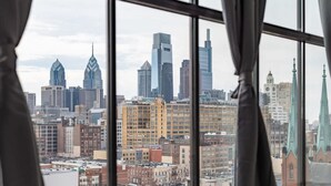 A cityscape through a window with curtains, featuring modern skyscrapers and historic buildings. - Sosuite 2BR Penthouse w W D Gym On-site Bar (Philadelphia)