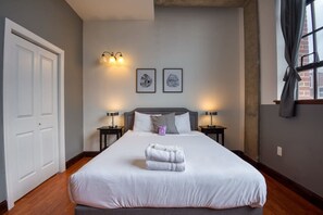 Une chambre d’hôtel avec un grand lit, deux lampes de chevet, une tête de lit et deux tableaux encadrés au mur.