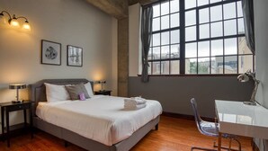 A bedroom with a bed, bedside tables, a desk, and a chair.