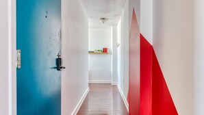 A hallway with a blue door, a red accent wall, and a wooden floor.