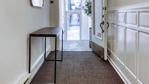 A hallway with a black table, a mirror, and a door leading to a bright room with a plant. - Sosuite 1BR Apt w W/d, Large Dining Seating (Philadelphia)