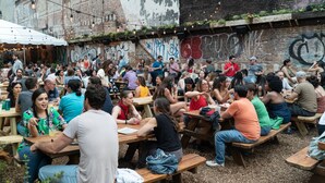 A crowded outdoor dining area with wooden picnic tables and string lights. - Sosuite Juliet Balcony 1BR Apt w W D Desk (Philadelphia)
