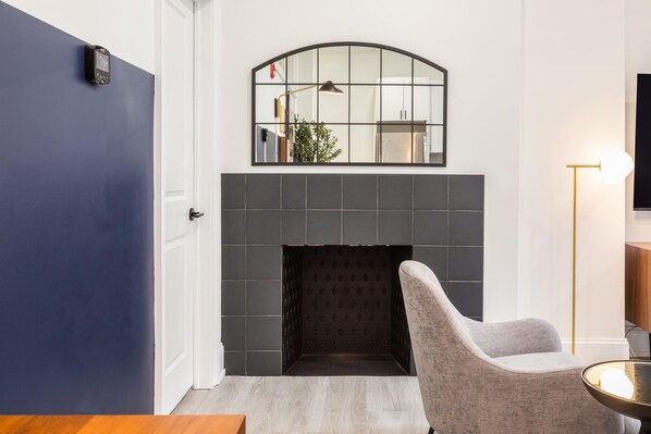 Un salon moderne avec une cheminée, un fauteuil gris et une petite table.