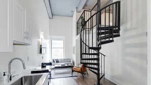 A modern kitchen with a stainless steel sink, a white countertop, and a black staircase with a metal railing. - Sosuite 2BR Loft w W/d, Gym, Lounge (Philadelphia)