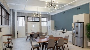 A modern kitchen with a dining area, featuring a large wooden table, multiple chairs, a built-in oven, and a stainless steel refrigerator. - Sosuite 2BR Loft w W/d, Gym, Lounge (Philadelphia)