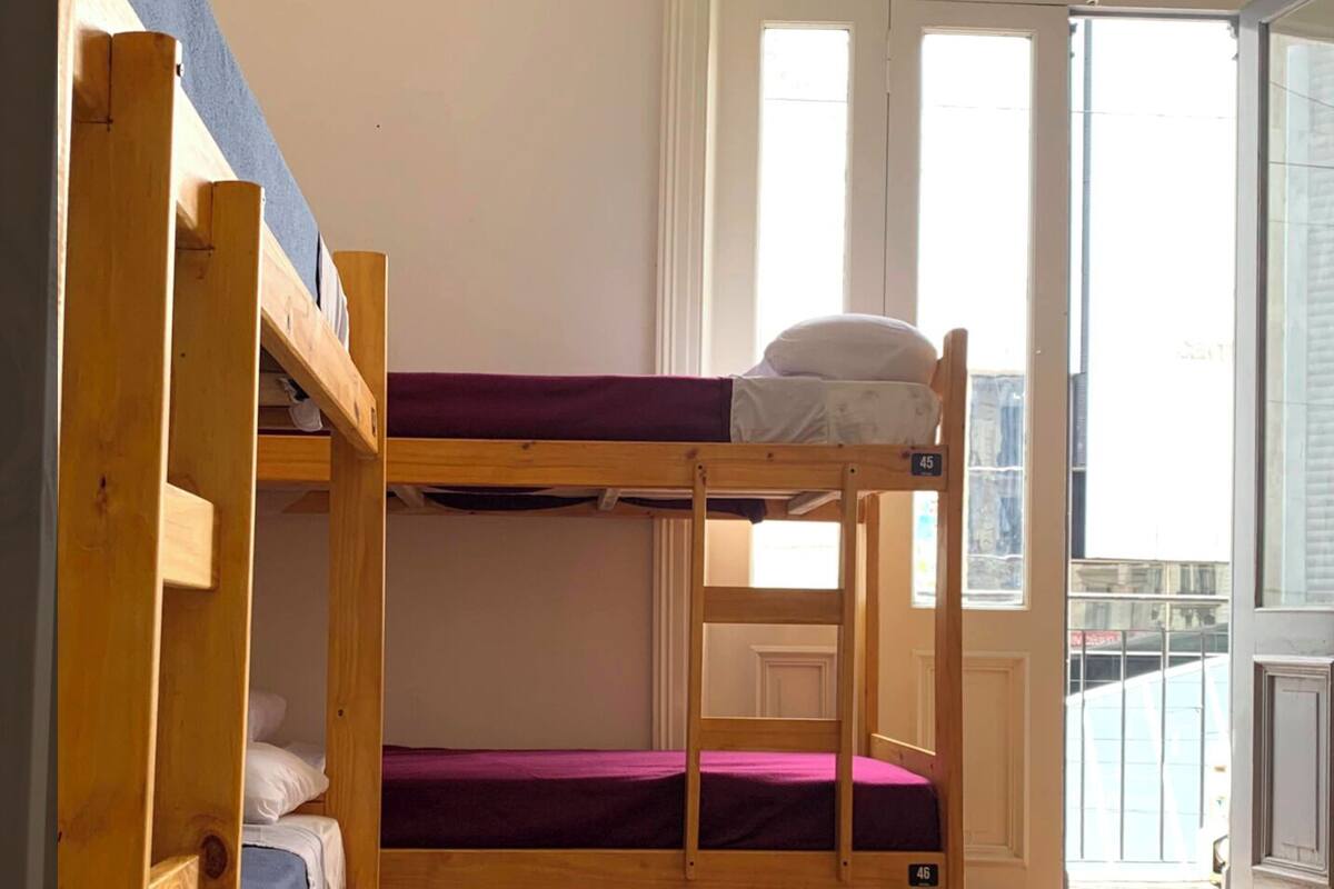A bunk bed room with wooden frames and purple bedding.