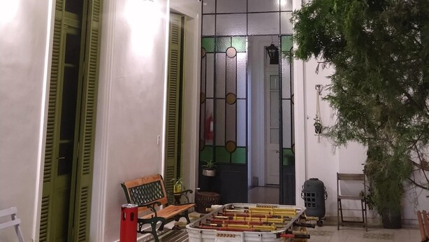 An outdoor seating area with a ceiling covered in artificial leaves, a bench, and a table with various items. - MiBAQ Hostel (Buenos Aires)
