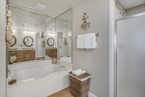 Un bagno con uno specchio grande, una vasca, un lavandino e un cesto di vimini.
