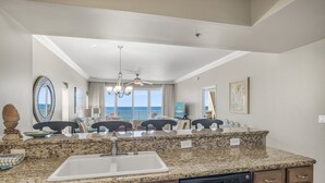 A kitchen with granite countertops, a dishwasher, and a large window overlooking the ocean. - Gulf Front with Beach Views & Large Balcony (Miramar Beach)